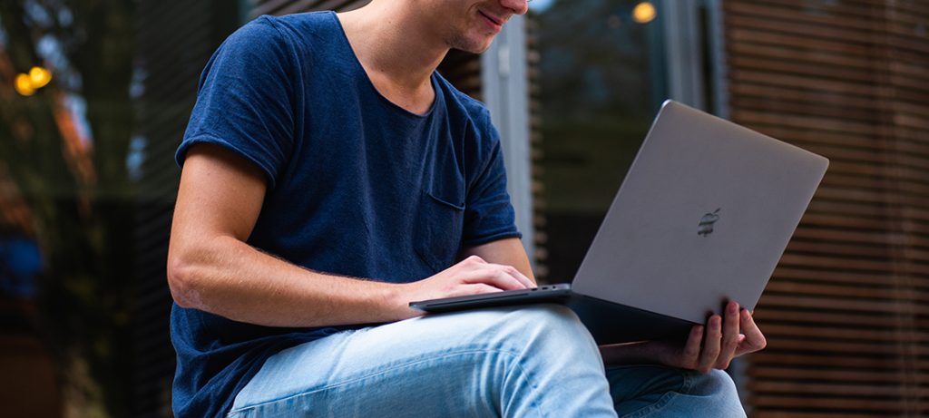 屋外でMacBookを操作する男性