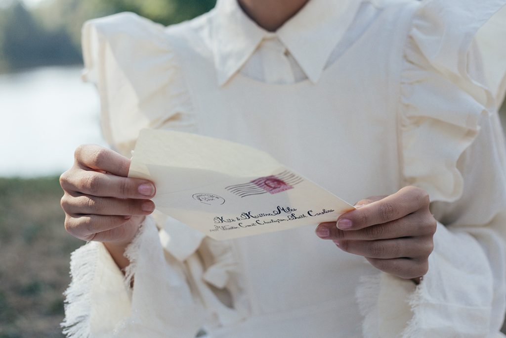 封筒を開いて手紙を取り出している女性の手元