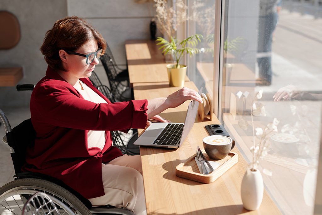 カフェのカウンター席でノートパソコンを広げる車椅子に乗った女性